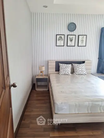 Modern bedroom with stylish decor and wooden flooring, featuring a cozy bed and elegant wall art.