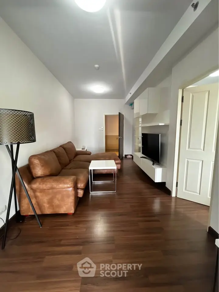 Modern living room with brown leather sofa and sleek TV unit in a cozy apartment.