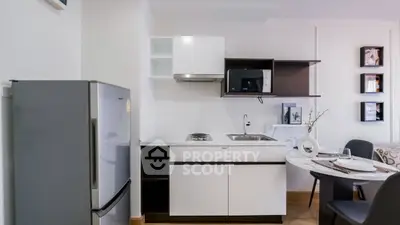 Modern kitchen with sleek appliances and dining area in stylish apartment.