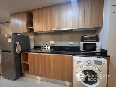 Modern kitchen with wooden cabinets, washing machine, and stainless steel appliances