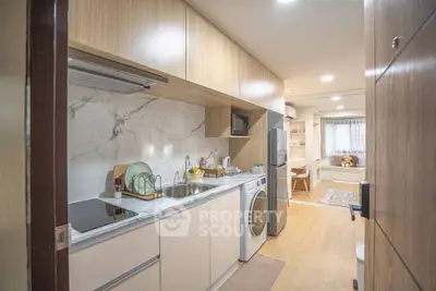 Modern compact kitchen with integrated appliances and cozy living area view