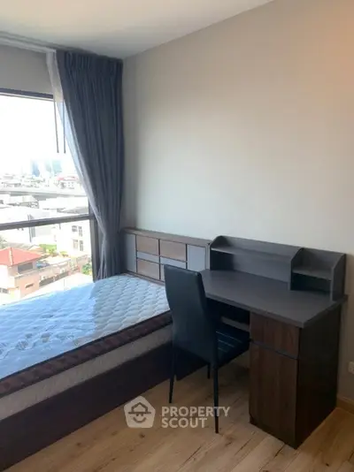 Modern bedroom with city view, featuring a sleek desk and comfortable bed, perfect for urban living.
