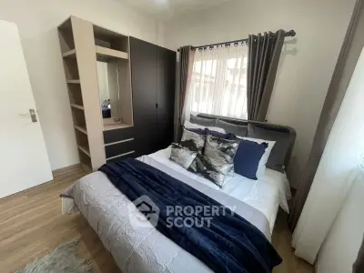 Cozy bedroom with stylish decor and ample natural light, featuring a modern wardrobe and plush bedding.