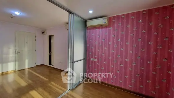Spacious living room with pink accent wall and sliding glass partition in modern apartment.