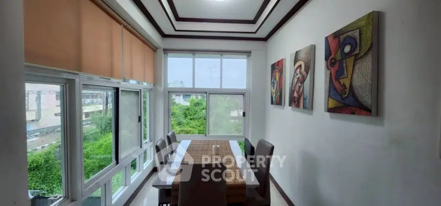 Elegant dining area with modern art and large windows offering lush green views.