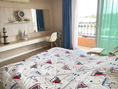 Charming bedroom with nautical decor and balcony access, featuring a cozy bed and stylish furnishings.
