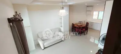 Spacious living room with elegant chandelier and dining area in modern apartment.