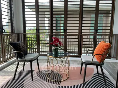 Chic balcony with stylish chairs and table, offering a serene view through modern louvered windows.