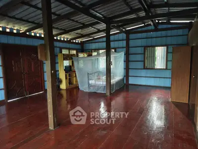 Spacious rustic living area with wooden floors and mosquito netting, perfect for tropical living.