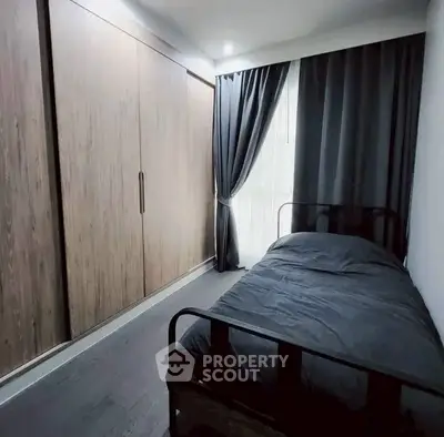Cozy bedroom with sleek black bed and large wooden wardrobe, perfect for modern living.