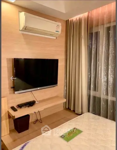 Cozy bedroom with modern TV setup and air conditioning, perfect for relaxation.