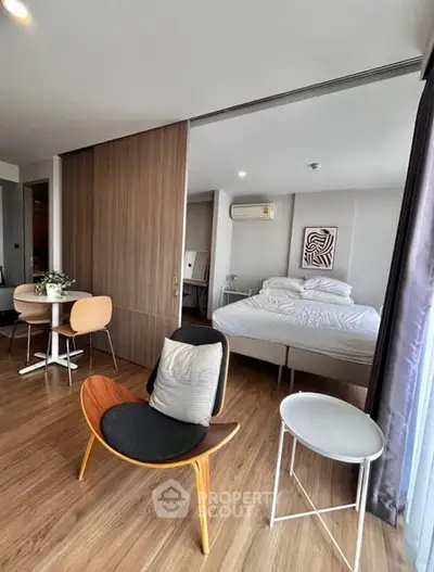 Modern studio apartment with open layout, featuring stylish furniture and wooden flooring.