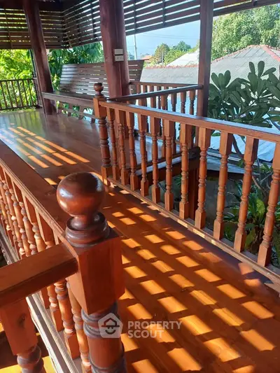 Charming wooden balcony with lush garden view, perfect for relaxation and outdoor enjoyment.