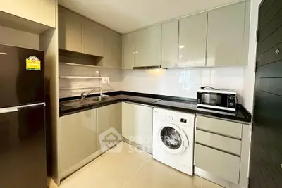 Modern kitchen with sleek cabinetry, washing machine, and microwave in a compact layout.