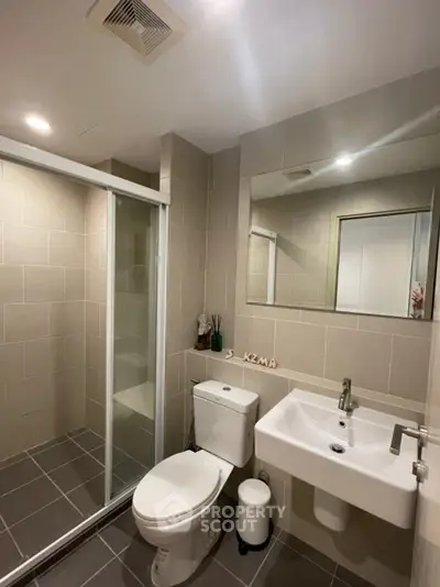 Modern bathroom with glass shower, sleek sink, and neutral tiles