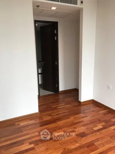 Spacious room with wooden flooring and open doorway, ideal for customization.