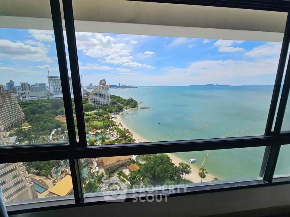 Stunning high-rise view of beach and city skyline from a modern apartment window.