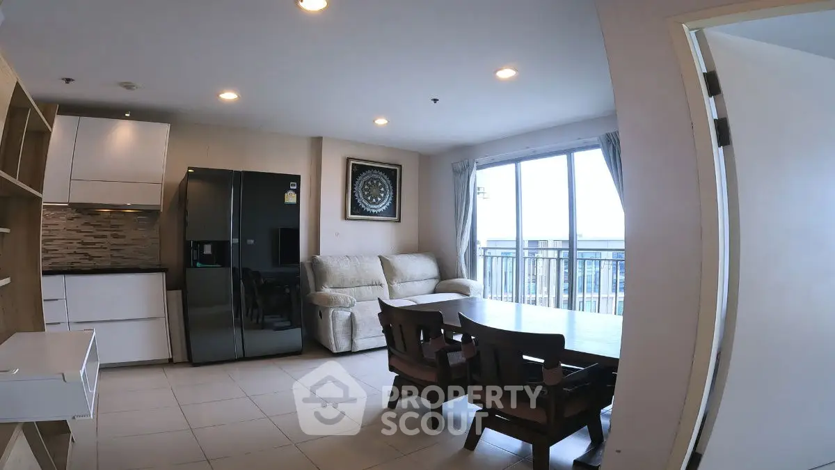 Modern living room with open layout and balcony view, featuring sleek furniture and natural light.