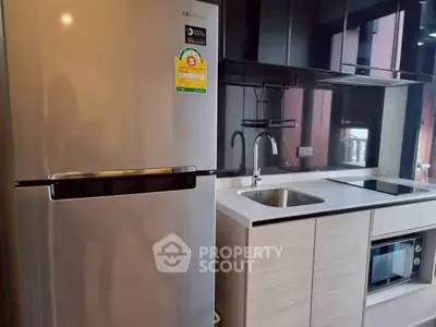 Modern kitchen with stainless steel fridge and sleek cabinetry in a stylish apartment.