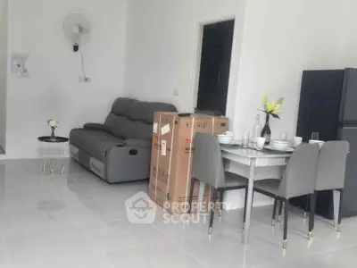 Modern living room with sleek furniture and dining area in a bright, open space.