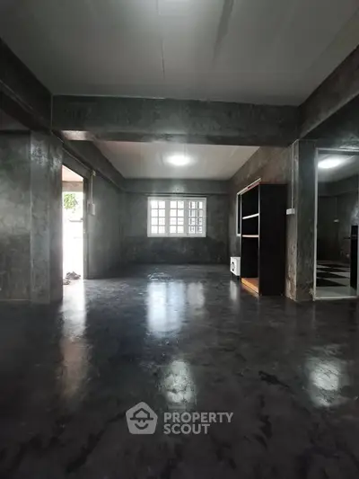 Spacious industrial-style living room with polished concrete floors and large windows.