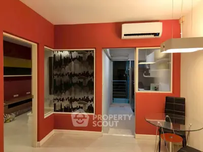 Modern living room with vibrant red walls, air conditioning, and stylish glass dining table.