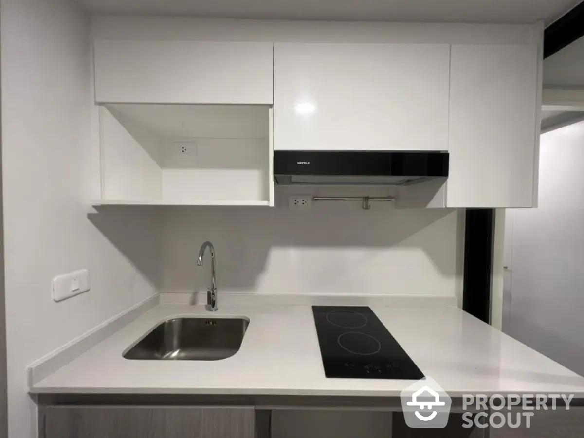 Modern minimalist kitchen with sleek white cabinetry and electric cooktop