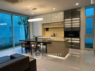 Modern kitchen with sleek cabinetry and island in open layout, featuring large windows and contemporary lighting.