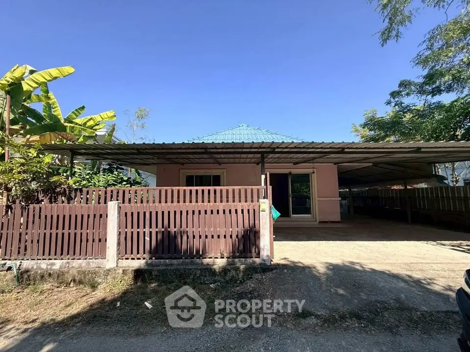 Charming single-story home with spacious carport and lush greenery, perfect for serene living.