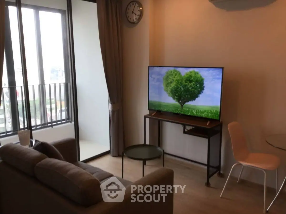 Modern living room with balcony view, stylish furniture, and large TV for a cozy urban lifestyle.