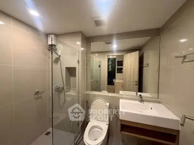 Modern bathroom with glass shower and sleek fixtures in a contemporary apartment.