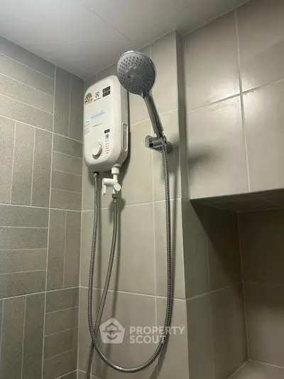 Modern bathroom with sleek showerhead and water heater in tiled setting.