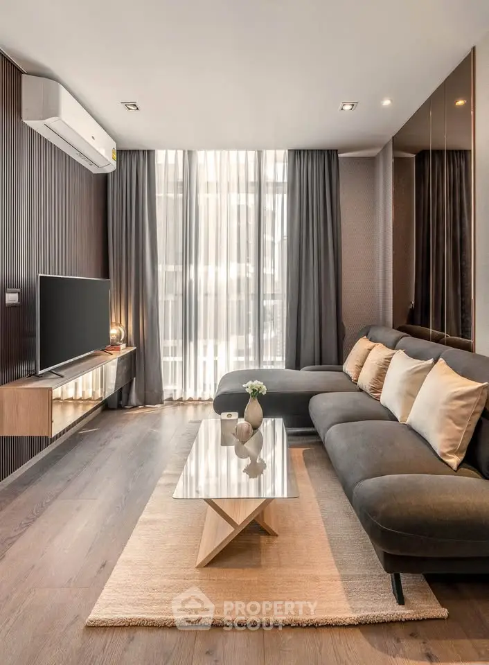 Modern living room with sleek design, featuring a large sectional sofa, wall-mounted TV, and floor-to-ceiling windows.