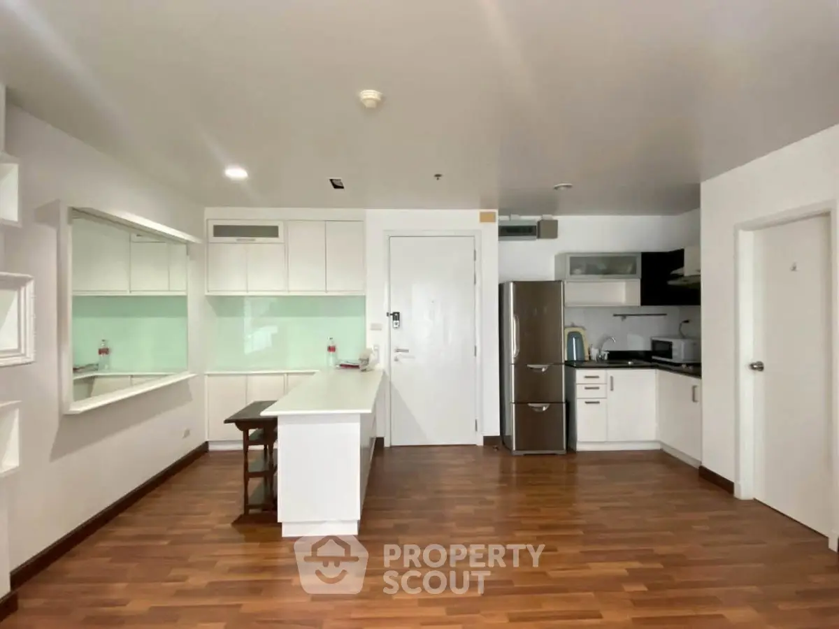 Modern kitchen with sleek white cabinets and stainless steel appliances in open layout apartment.
