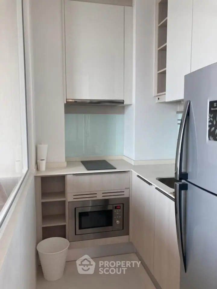 Modern kitchen with sleek appliances and minimalist design, featuring built-in oven and glass backsplash.