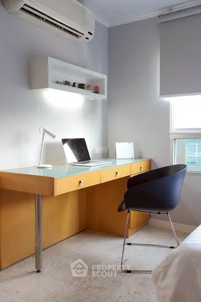 Modern study room with sleek desk, chair, and air conditioning in a bright apartment.