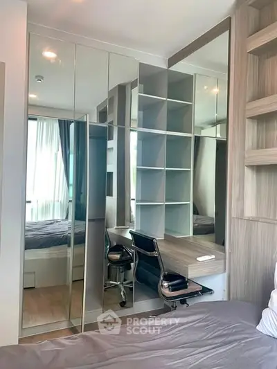 Modern bedroom with mirrored wardrobe and built-in study desk, featuring sleek design and natural light.