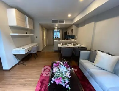 Modern living room with elegant decor and open kitchen layout, featuring stylish furniture and ambient lighting.