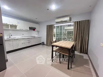 Modern kitchen with open layout and dining area, featuring sleek cabinetry and air conditioning.