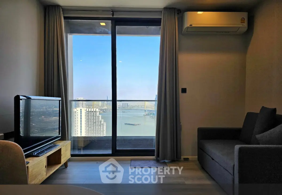 Modern living room with stunning city and river view from large window, featuring cozy sofa and TV setup.