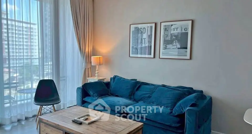 Chic living room with blue sofa, modern decor, and large window offering natural light.