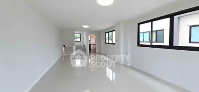 Spacious and bright living area with large windows and glossy tiled floors.