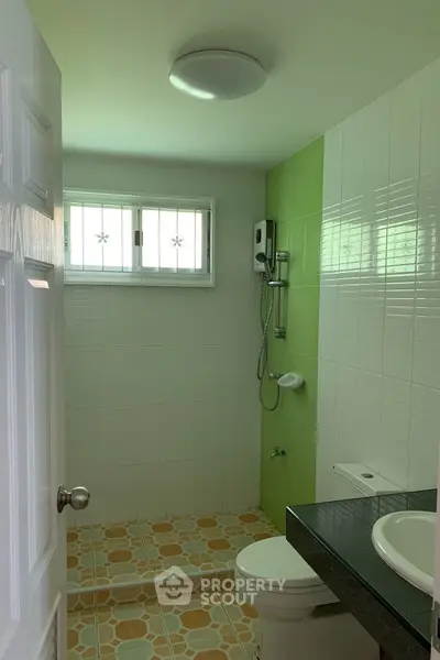 Compact bathroom with modern shower and green accent wall tiles