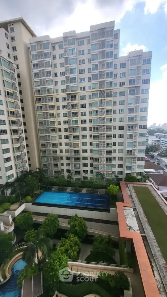 High-rise residential building with pool and lush greenery, offering urban living with scenic views.