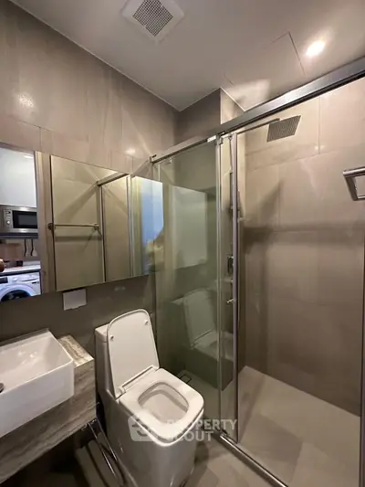Modern bathroom with glass shower and sleek fixtures in a contemporary apartment.