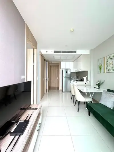 Modern open-layout living room with sleek kitchen and dining area, featuring contemporary furniture and bright lighting.