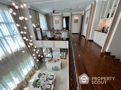 Luxurious multi-level living space with elegant chandelier, hardwood floors, and a sophisticated open layout connecting living and dining areas.