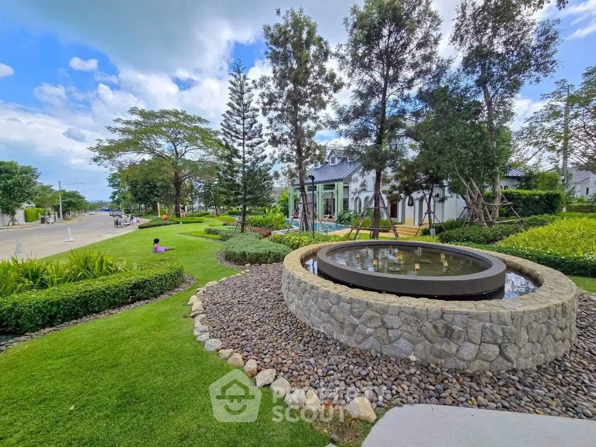 Beautiful landscaped garden with stone fountain in a serene residential neighborhood.