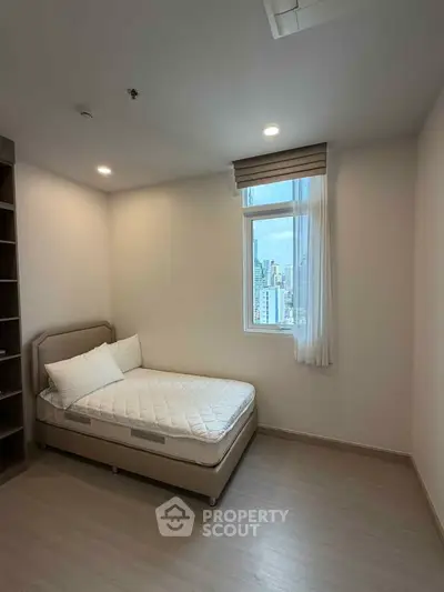 Cozy bedroom with city view, featuring a comfortable bed and ample natural light.