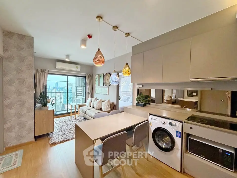 Modern open-plan living room with kitchen, featuring stylish lighting and city view balcony.